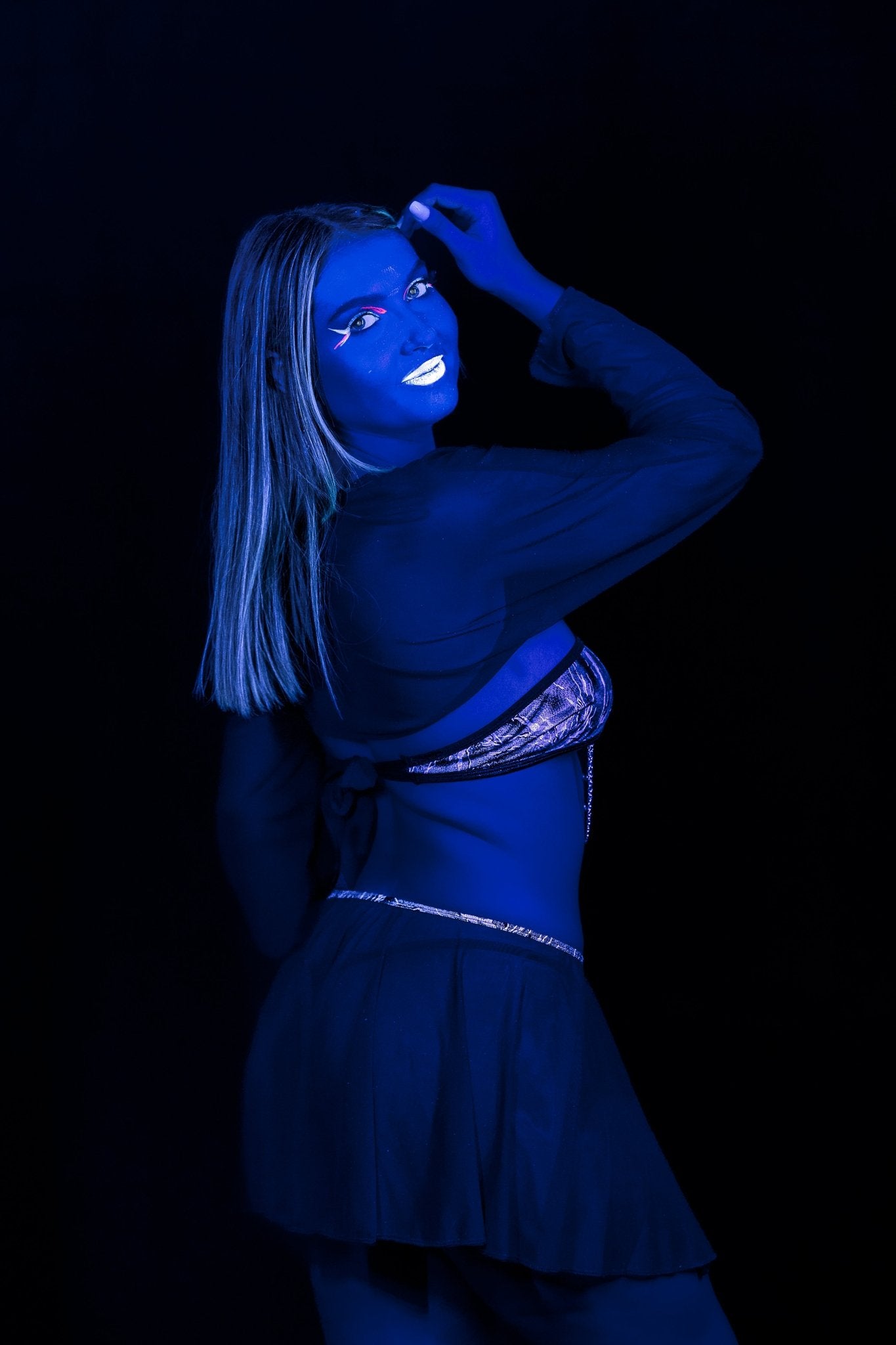 A woman poses against a black background wearing the Black Mesh Shrug – Rave Festival Sheer Cover-Up by Brigitewear International, LLC, paired with a skirt and bikini top, her body and face painted blue.