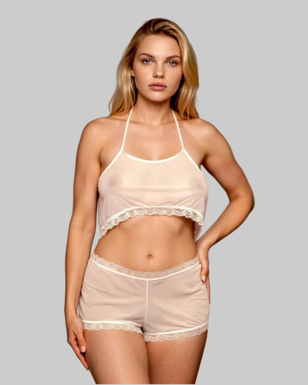 Model wears the Malibu Nights Sheer Mesh Cropped Tank by Brigitewear International, LLC in light beige with lace trim, standing against a neutral gray background.