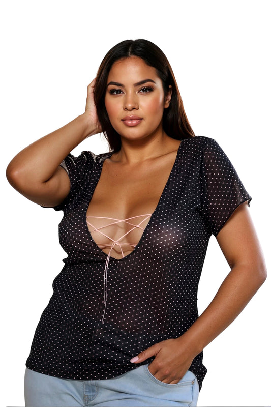A woman poses with one hand on her head, wearing the Brigitewear International, LLC Long Lace Up T Shirt, featuring black polka dots and a deep neckline with lace-up detail.
