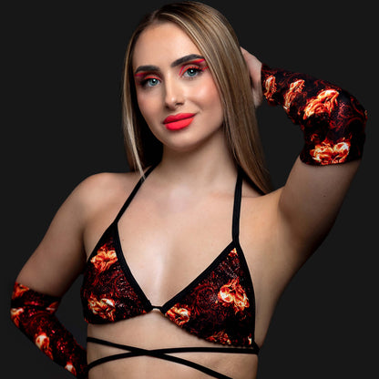A woman poses confidently on a black background wearing Brigitewear International's Inferno Heart Pointed Gloves, featuring a striking flame pattern and bold red makeup.