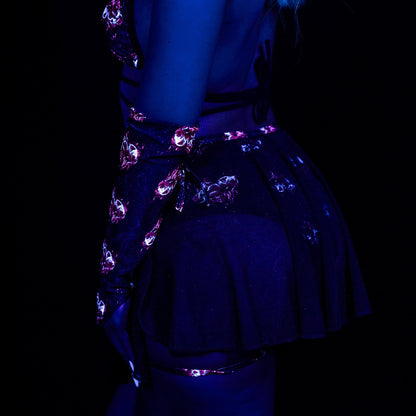 Under blacklight, a person with neon makeup, glowing hair streaks, and bright nails wears a dark floral outfit styled with Brigitewear International's Inferno Heart Pointed Gloves.