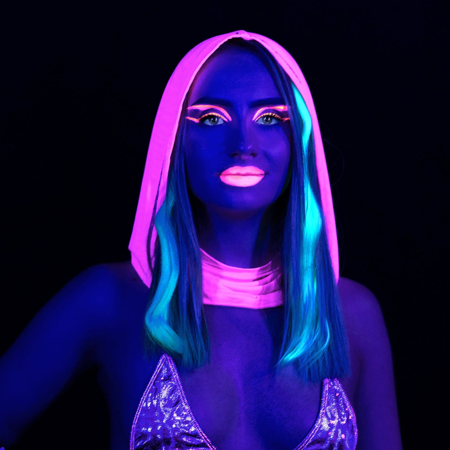 A person wearing the Grape Babe Mesh Hood by Brigitewear International, LLC, with glowing neon makeup and hair, showcases vivid colors under blacklight on a dark background.