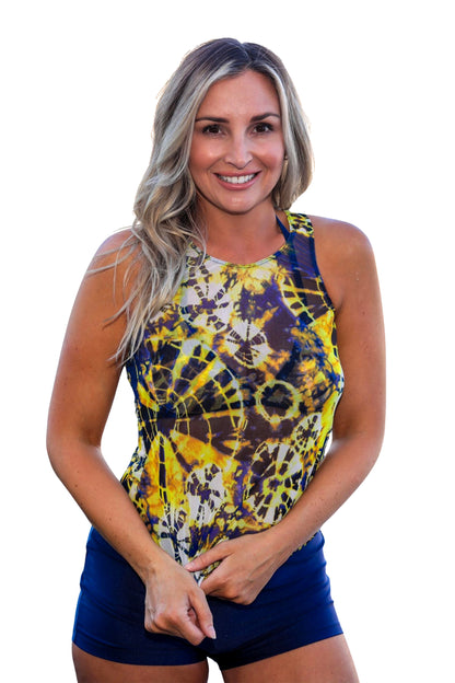 Smiling woman wears the Navy Kaleidoscope Classic Tank, a sheer mesh top by Brigitewear International, LLC, paired with dark shorts against a white background.