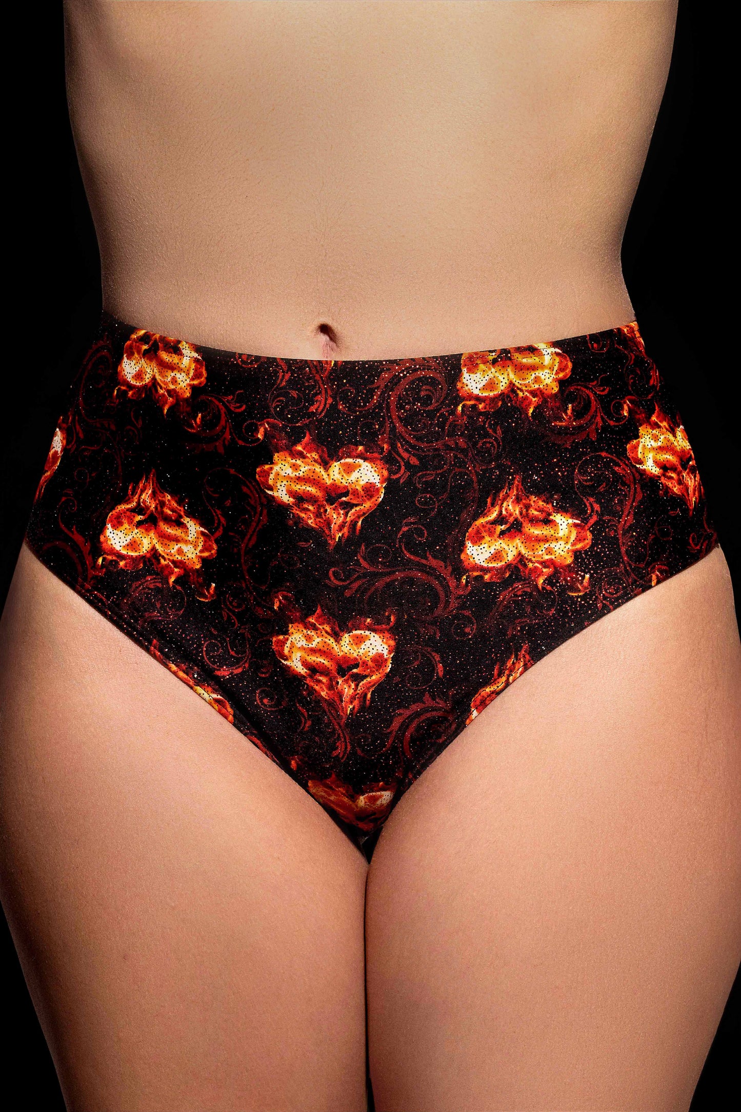 Someone wearing Brigitewear International, LLC's Inferno Heart High Waist Bottoms, featuring a bold black design with red and orange flame patterns.