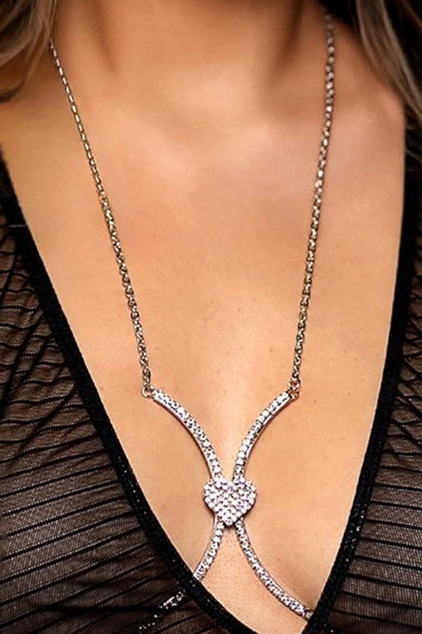 A woman wearing the Boobie Bling Sparkling Rhinestone Bikini Chain by Brigitewear International, LLC over a sheer black, striped top.