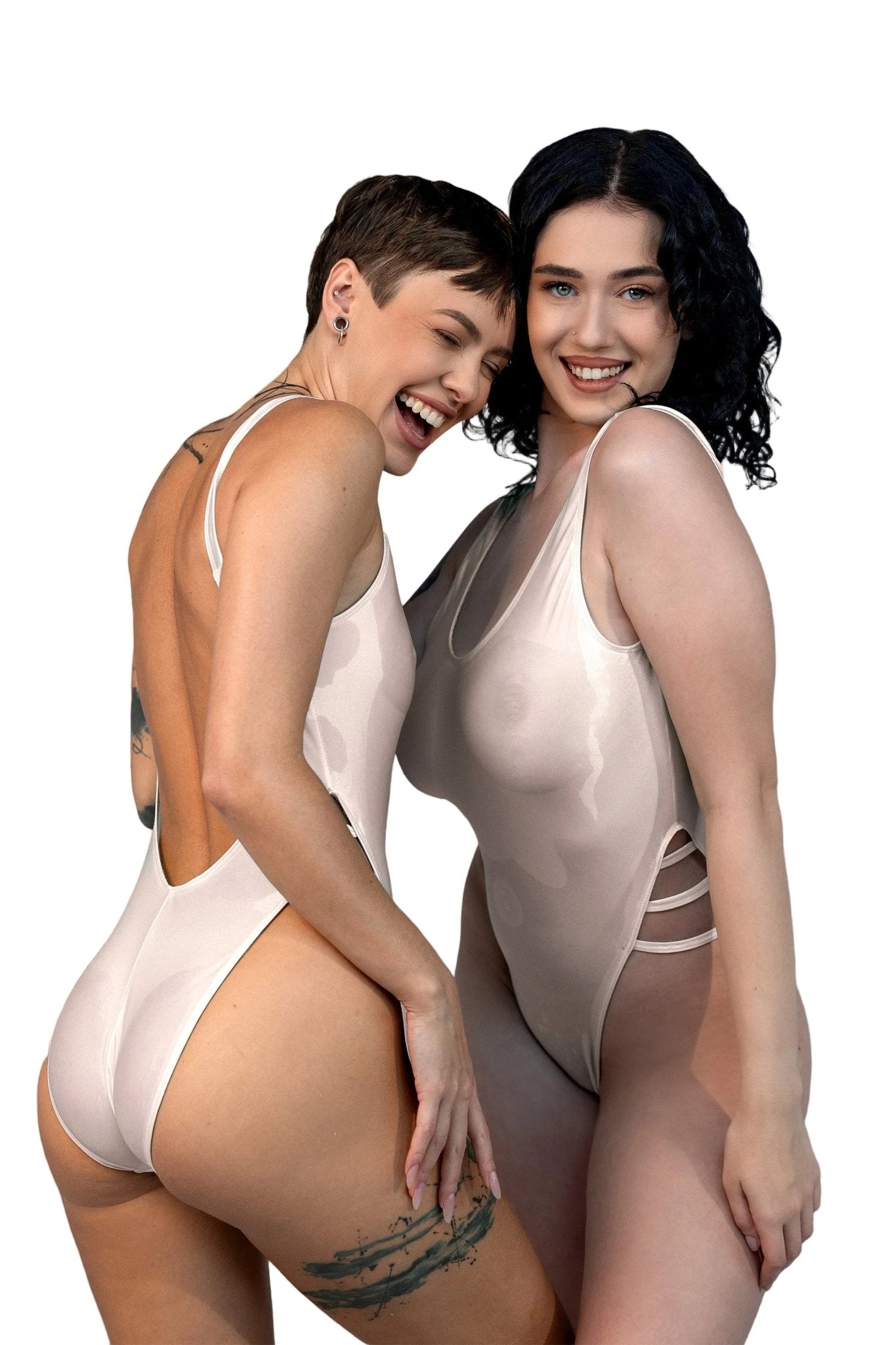 Two women smile and pose together in Brigitewear International, LLC’s Breezy See Through One Piece Swimsuits against a white background.