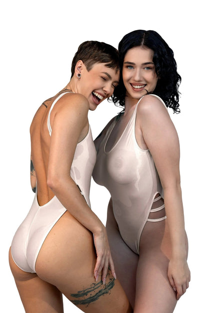 Two women smile and pose together in Brigitewear International, LLC’s Breezy See Through One Piece Swimsuits against a white background.