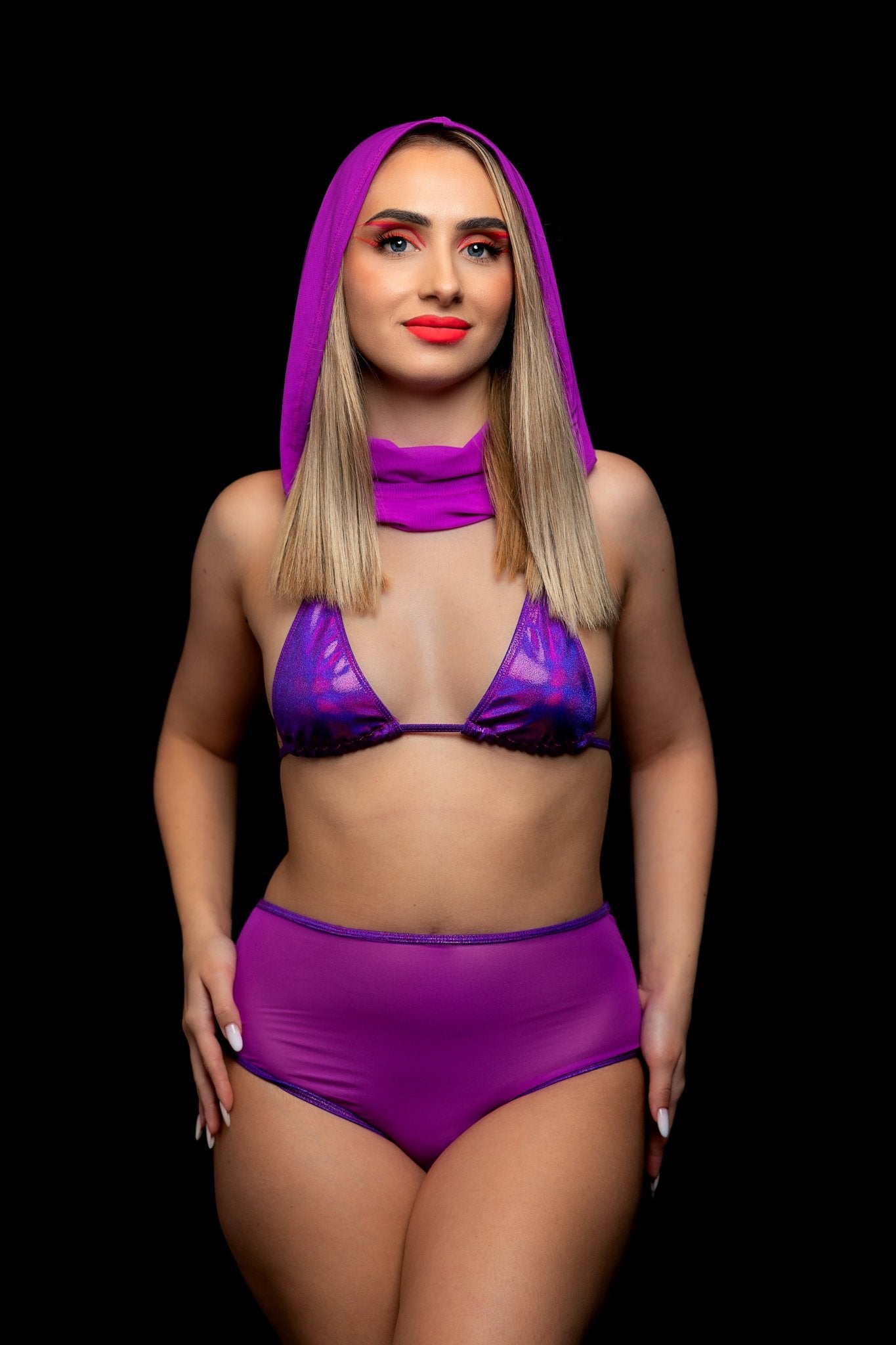 Woman wearing the Candescent Grape Sexy Triangle Top by Brigitewear International, LLC, standing against a black background, looking forward and smiling.