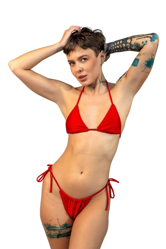 A person models the Brigitewear International, LLC Cannes Bikini Top on a sandy beach with the ocean and blue sky in the background.