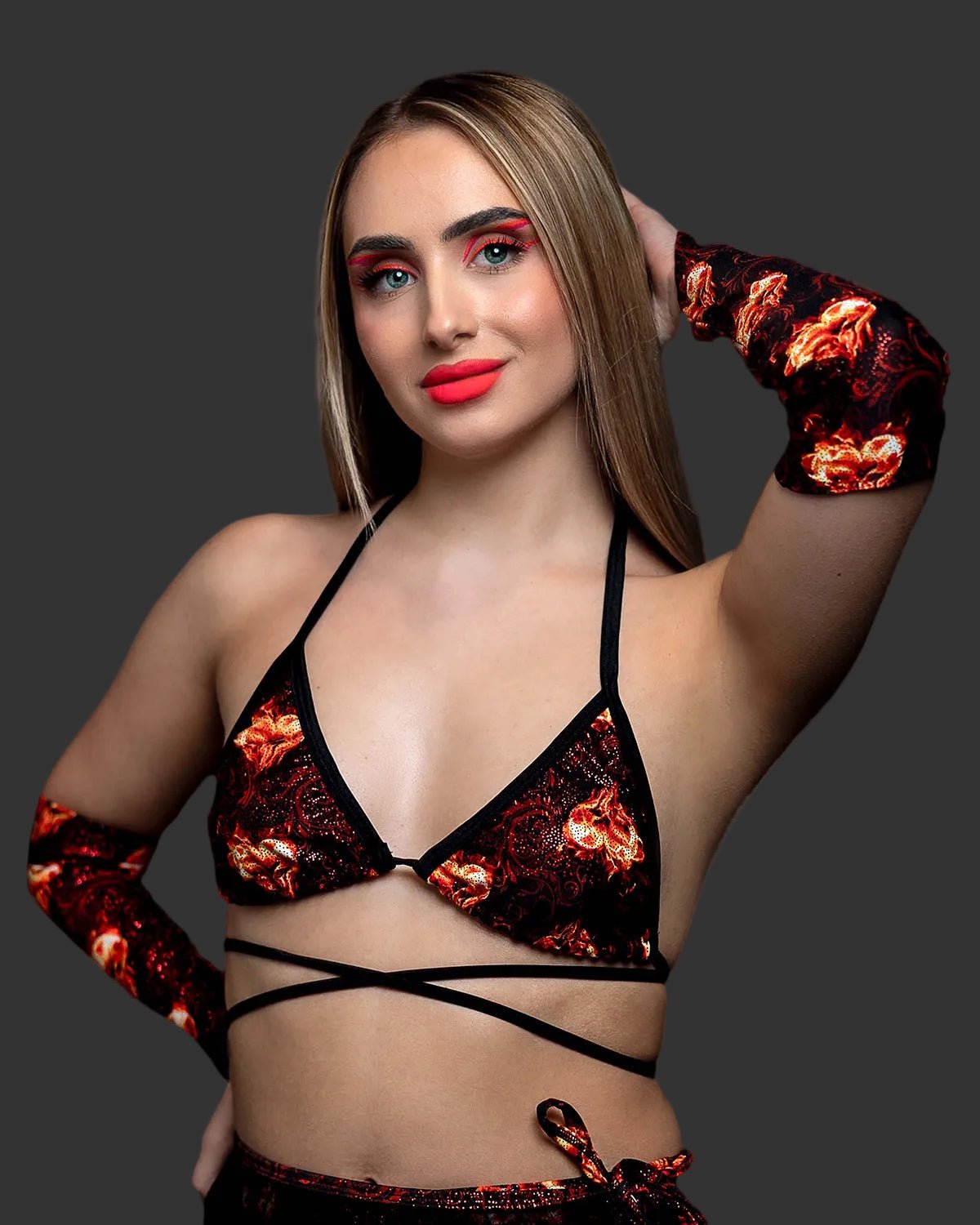 A woman wears a bikini top and Inferno Heart Pointed Gloves-Rave Festival with a black and red flame heart pattern.