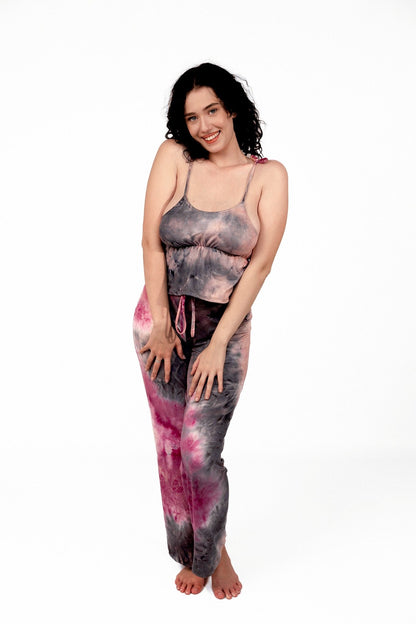 Smiling woman with curly dark hair stands barefoot, wearing Brigitewear International, LLC’s Long Loungewear Pants-Soft&Cozy and a tie-dye tank top.