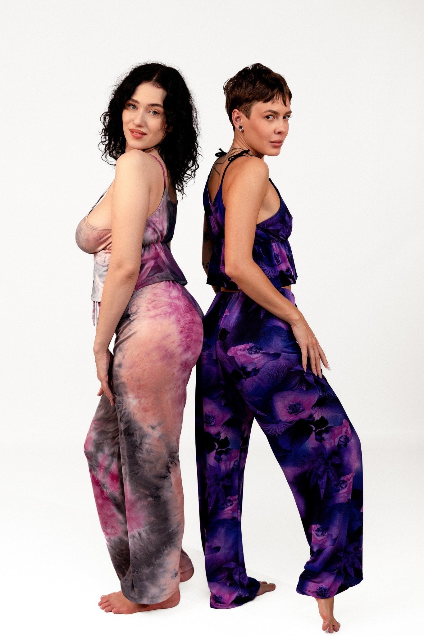 Two women wear Brigitewear International, LLC's Long Loungewear Pants-Soft&Cozy in vibrant patterns, standing back-to-back against a white background.