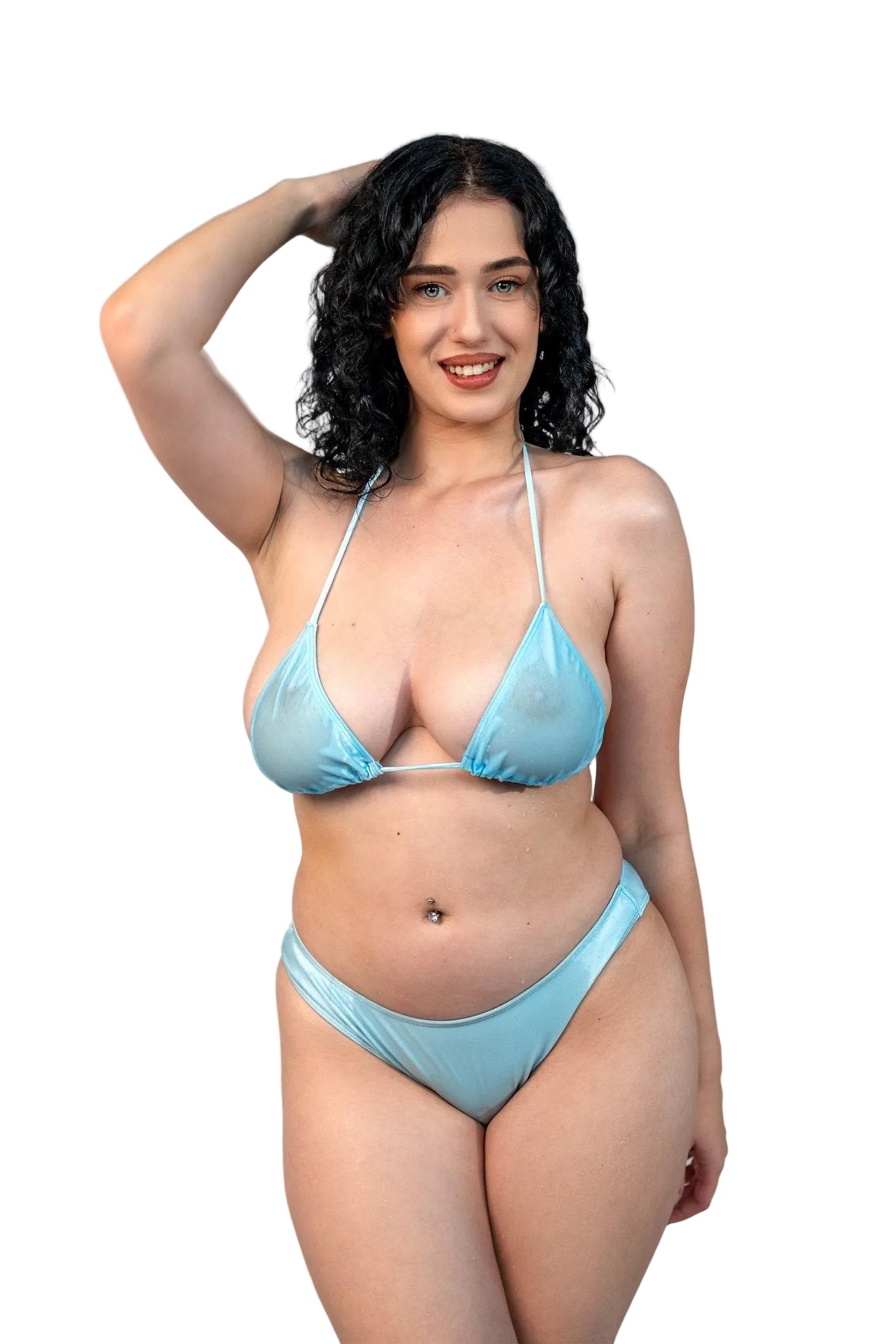 Smiling woman wears the Sheer Cannes Bikini Top by Brigitewear International, LLC on a sandy beach with waves and ocean in the background.