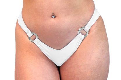 Model wearing Brigitewear International's V-Bottom Thong & Rio Bikini Bottoms in white, featuring silver ring accents; close-up of lower torso and hips.
