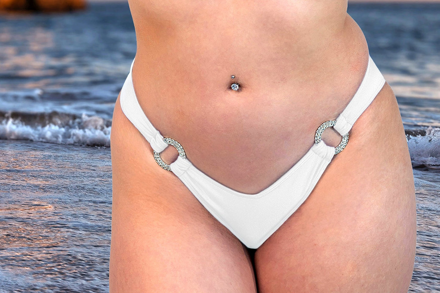 Close-up of a person wearing the Brigitewear International V-Bottom Thong & Rio Bikini Bottoms with ring details, standing by the ocean.