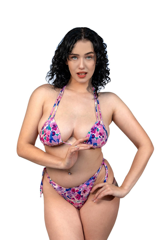 A woman with curly dark hair poses in the Violet Garden Top by Brigitewear International, LLC against a white background.